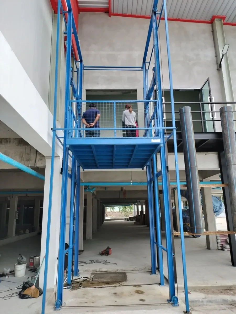 พนักงานยืนบนแพลตฟอร์มลิฟท์ขนของ 4 เสา 1 ตัน Mactech ขณะใช้งานจริงหน้างาน