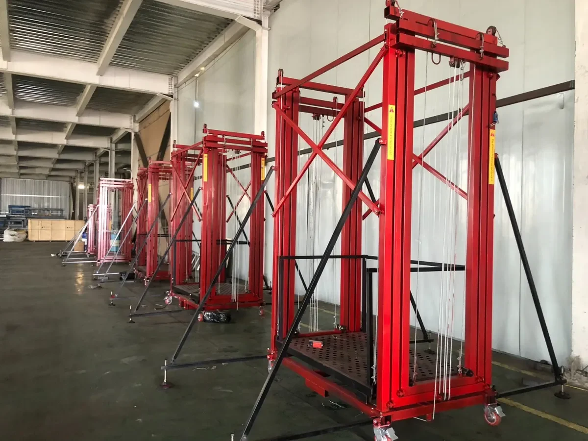 โครงนั่งร้านไฟฟ้าเคลื่อนที่ Mactech หลายชุดเรียงในโรงงาน แสดงโครงเหล็ก สลิงยก และล้อเลื่อน